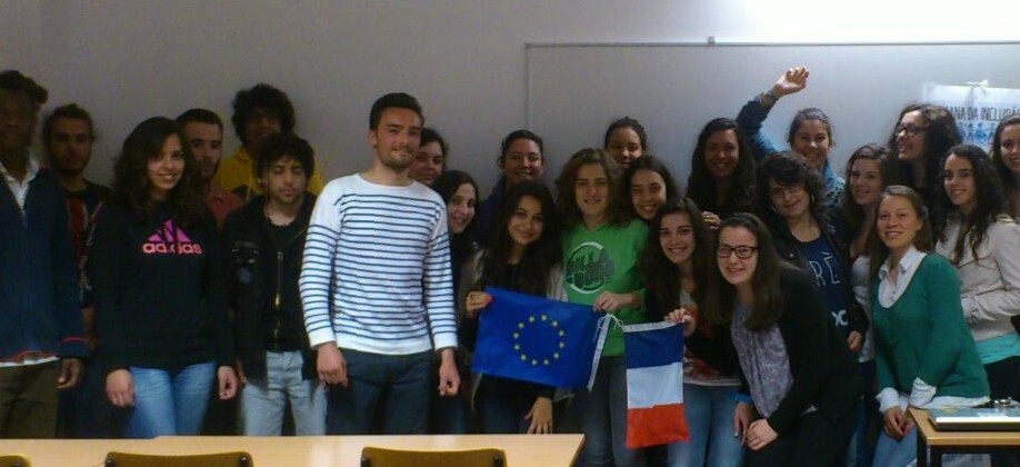 Grupo de estudantes em pé numa sala de aula.